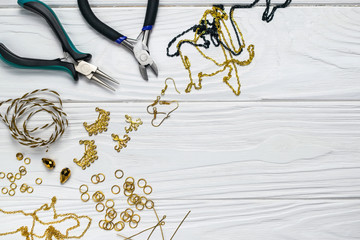 Jewelry findings handmade craft composition with pliers beads embellishments on white wooden...