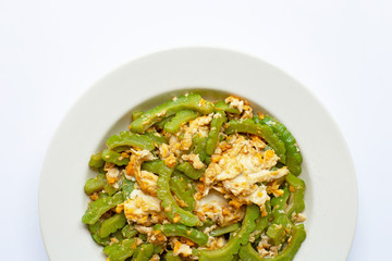 Stir-fried egg with bitter melon on a white dish on white.