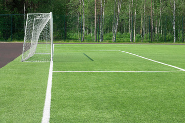 Football goal in the field. From which the shadow on a green grass falls. A look with a side.
