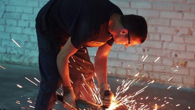 Man works circular saw in slow motion. Flies of spark from hot metal. The man's hard work. Man Chlef and smooth surface. Man worked over the steel. close-up of hand and electric saws metal. Close-up