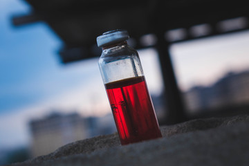 Erlenmeyer flask with red solution standing on a stone surface.