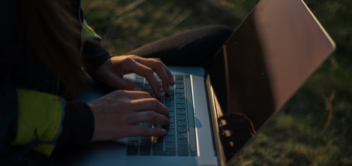 Close view of young woman working on laptop in the fields 