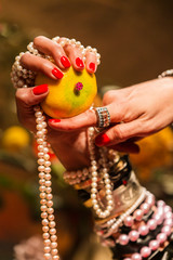 Cropped Hand holding Orange decorated with Jewellery