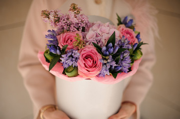 Girl holding a white spring box of tender pink and violet flowers