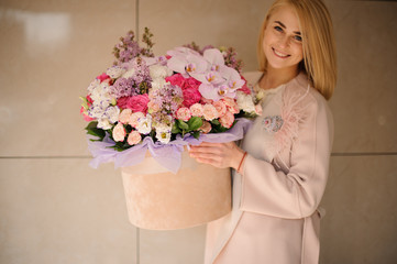 Smiling girl holding a huge spring box of tender multicolored pink flowers