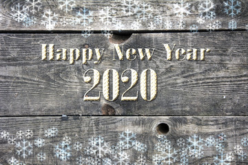 Happy new year wishes and golden 2020 number on wooden boards with snow flakes