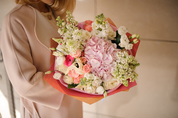 Girl in the coat holding a bouquet of tender pink and white flowers