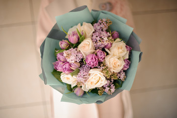 Woman holding a bouquet of tender bright violet and peach color flowers