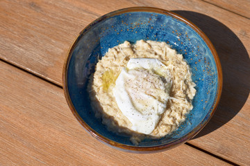 Morning Breakfast in a blue plate on the table. savoury oatmeal with fried egg, top view. Healthy balanced breakfast food