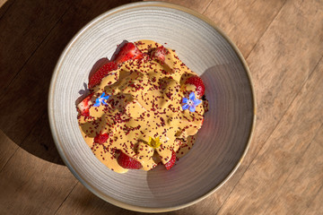 Morning breakfast in a blue plate on the table. Ice cream with caramel and fresh strawberries. selective focus.
