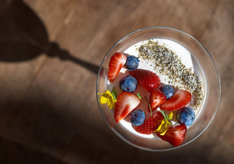Dessert panna cotta with daisy flower. fresh strawberries and berries on wooden background, selective focus.