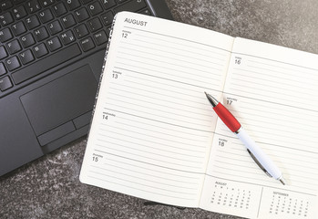 top view of open calendar or planner and pen on laptop computer