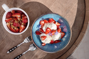 Morning breakfast in a blue plate on the table. vanilla Ice cream with caramel and fresh strawberries. selective focus.