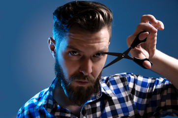 Portrait male hairdresser holding scissors , looking at camera, studio shot 