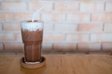 Iced chocolate in a tall glass with fresh milk foam on top