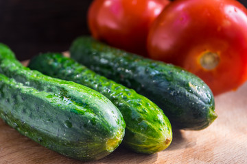 Cucumbers and tomatoes for cooking healthy food on a cutting board close-up