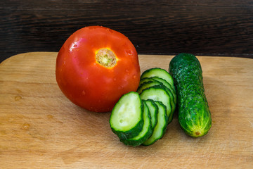Whole tomato and cucumber for healthy food on a cutting board
