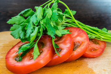 Sliced ​​tomatoes and parsley for salad, vegetarian food on a cutting board