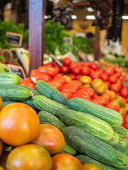 several types of tomatoes and vegetables on the shelf of a fruit store