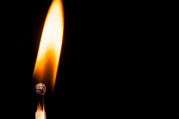 Fototapeta premium Burning wooden match close-up, on a black background. Isolate Macro shooting.