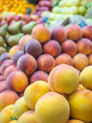several types of  peaches and fruit on the shelf of a fruit store