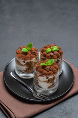 Classic tiramisu dessert in a glass on dark concrete background