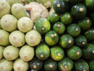 several types of cucumbers and peppers on the shelf of a fruit shop