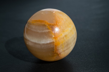 Opal moonstone yellow in the shape of a sphere of a ball on a black background close-up
