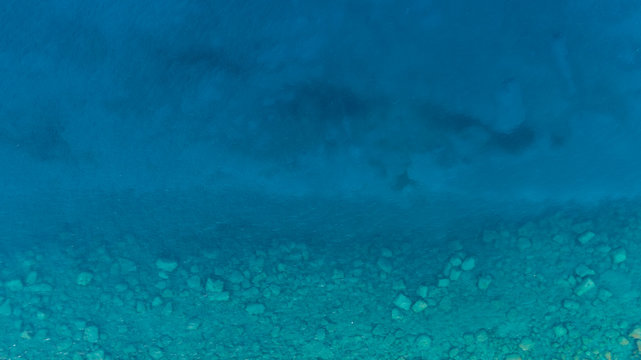 Background image of the turquoise sea. Deep sea and corals. Aerial drone shot of turquoise water.