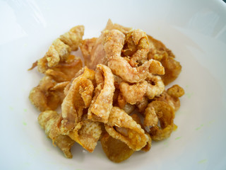 Close up of deep-fried chicken skins in a white bowl.