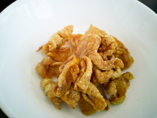 Close up of deep-fried chicken skins in a white bowl.