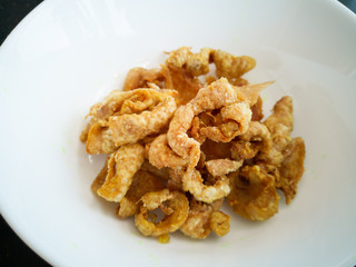 Close up of deep-fried chicken skins in a white bowl.