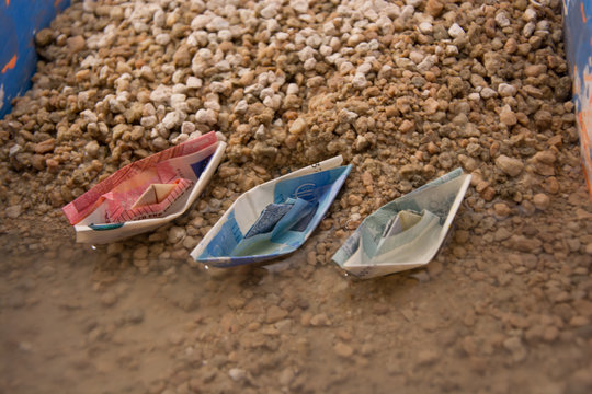 Dinero arrastrado por el agua, Barcos de papel de billetes de euro llegando a tierra