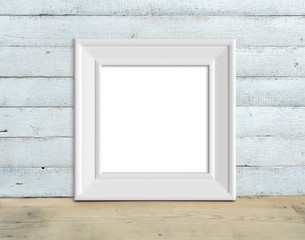 Square Vintage White Wooden Frame mockup stands on a wooden table on a painted white wooden background. Rustic style, simple beauty. 3d render.