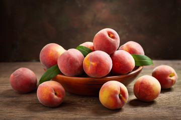 fresh peaches with leaves in a bowl
