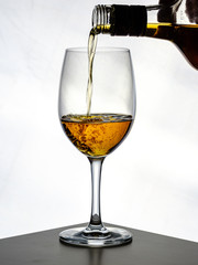 transparent wine glass with cognac being poured in