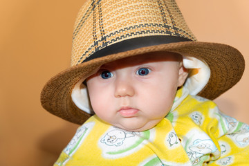 Portrait of a child, a little girl in a straw hat, in the studio on a beige background.