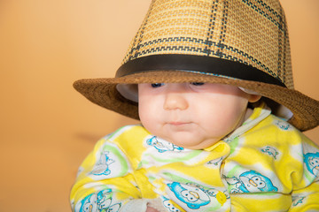 Portrait of a child, a little girl in a straw hat, in the studio on a beige background.