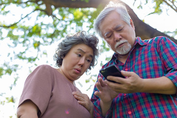 Grandmother and grandfather reading bad news or message that makes elderly woman and elderly man get nervous, stressed and shocked that one of family get accident or illness. Elder couple get unhappy