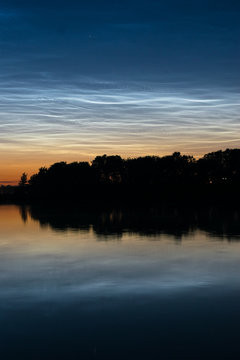 Noctilucent clouds (night shining clouds): blue silvery colored clouds in the upper atmosphere over a dutch lake close to Gouda, Holland.