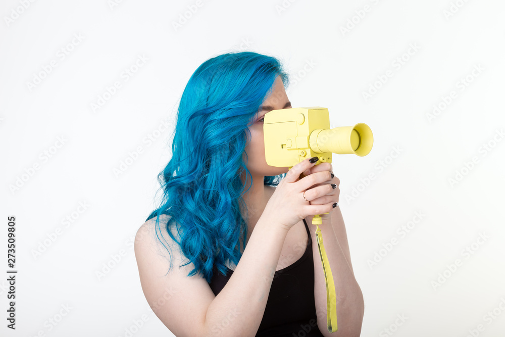 Wall mural People, hobby and fashion concept - Beautiful girl with blue hair hold yellow retro camera on white background