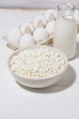 bowl of fresh farm cottage cheese and eggs on white wooden  background, vertical