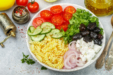 Greek salad with fusilli paste, lettuce, tomatoes, cucumber, feta cheese, red onions and black olives. Dressed with olive oil. A delicious Mediterranean appetizer. Selective focus