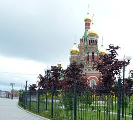 Obraz premium city street with built temples and churches and growing trees and bushes on a summer day