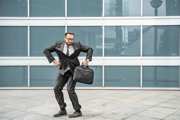Cheerful business man dancing near the office building on the street