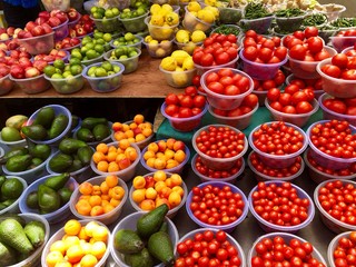 Fruit market with various colorful fresh fruits and vegetables sold in plastic buckets in...