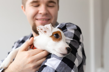 Obraz premium people, pets and animals concept - close up of young man holding jack russell terrier puppy