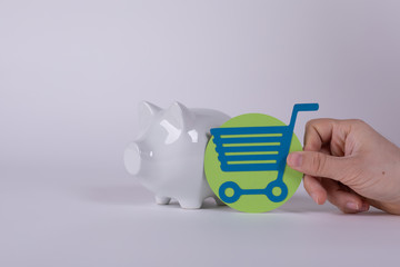 Obraz premium Shopping cart versus pig money box. Save money against spending money.