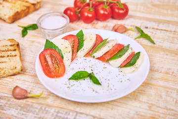Italian caprese salad with sliced tomatoes, mozzarella cheese, basil, olive oil.