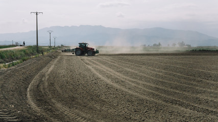 tractor plowing a dusty field